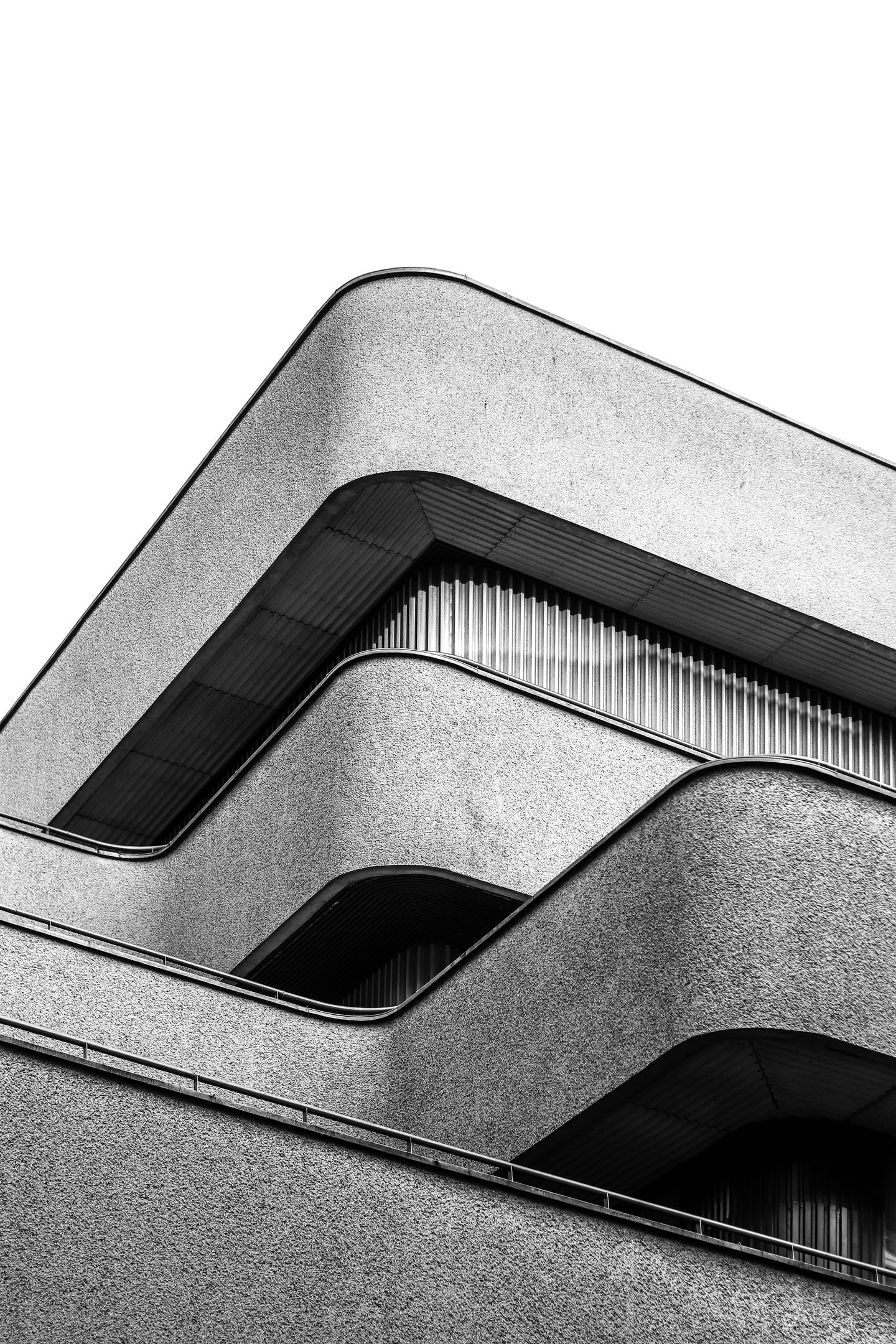 Curved concrete facade with bands against a grey sky